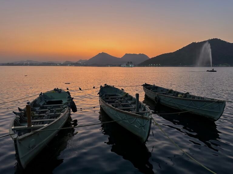 Fateh Sagar Lake Sunset: Golden hues of sunset over Fateh Sagar Lake with boats gliding on the serene waters.