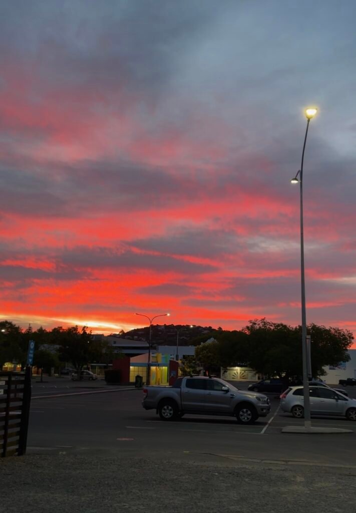 Sunset over Buxton Square car park with parked vehicles, a permitted freedom camping area in Nelson, New Zealand