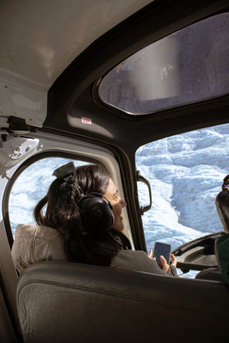 View from inside a helicopter flying over Franz Josef Glacier with snowy ice formations below