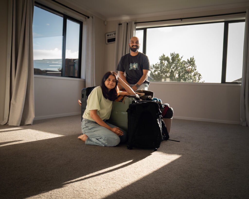 Sagar and Ami sitting with their bags in their living room on the day they left their home to travel New Zealand full time
