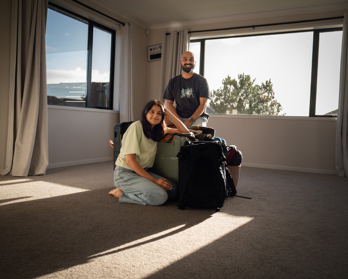 Sagar and Ami sitting with their bags in their living room on the day they left their home to travel New Zealand full time