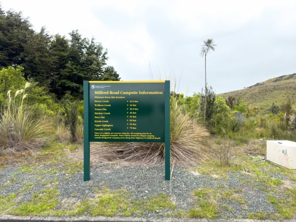 DOC Milford Road Campsite Information sign listing distances to DOC campsites New Zealand including Kiosk Creek in Fiordland