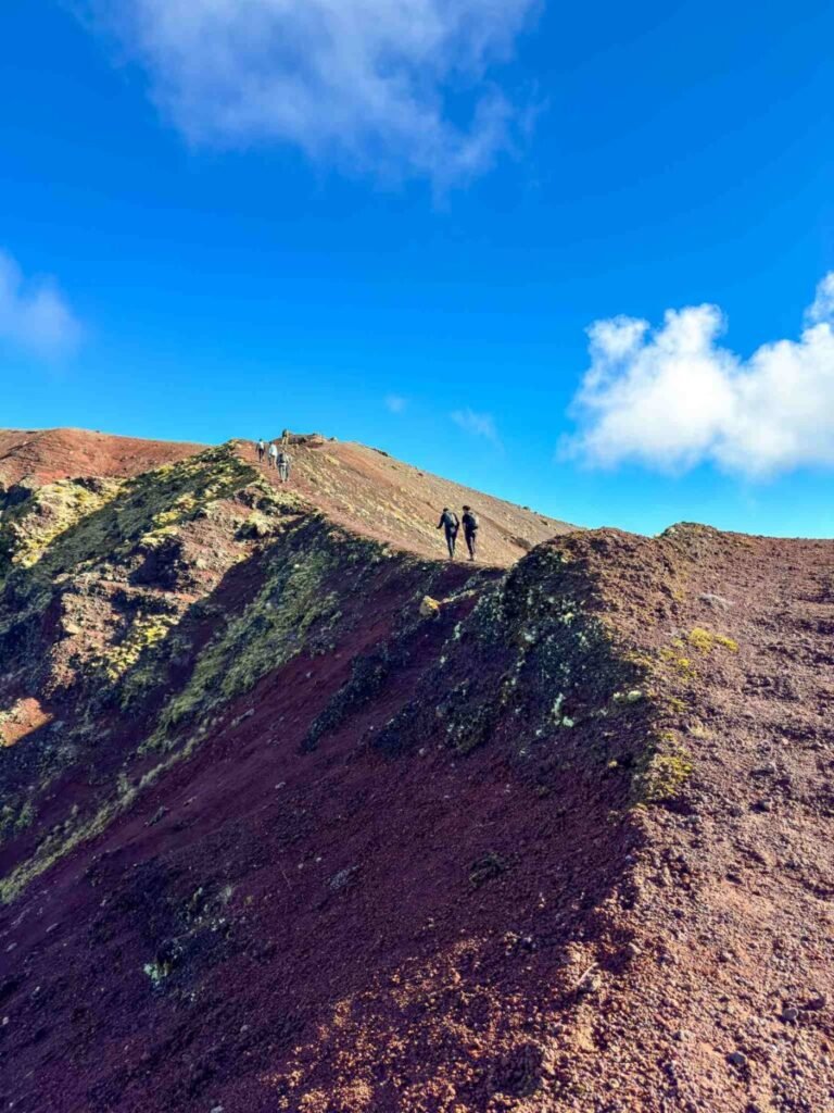 Hikers walking the rocky volcanic ridge of Mount Tarawera showing the moderate difficulty of the Kaitiaki Adventures guided hike near Rotorua