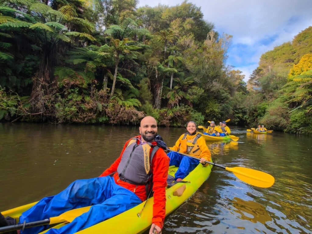 Kayakers paddling a native bush lined river on a day trip near Rotorua, New Zealand
