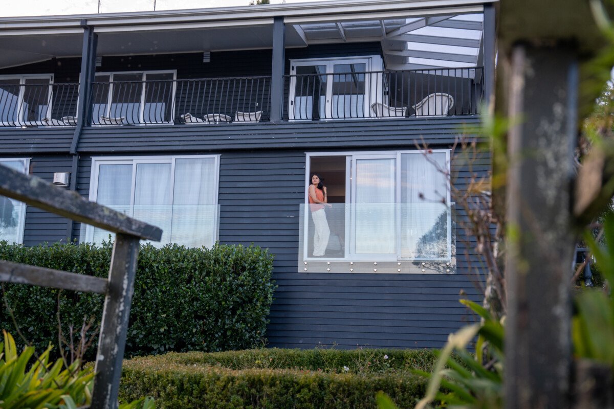 Guest standing on balcony at a lakefront Rotorua accommodation property