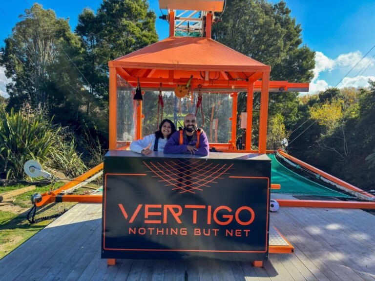 Sagar and Ami smiling in front of the Vertigo Nothing But Net sign at Velocity Valley Rotorua after the freefall