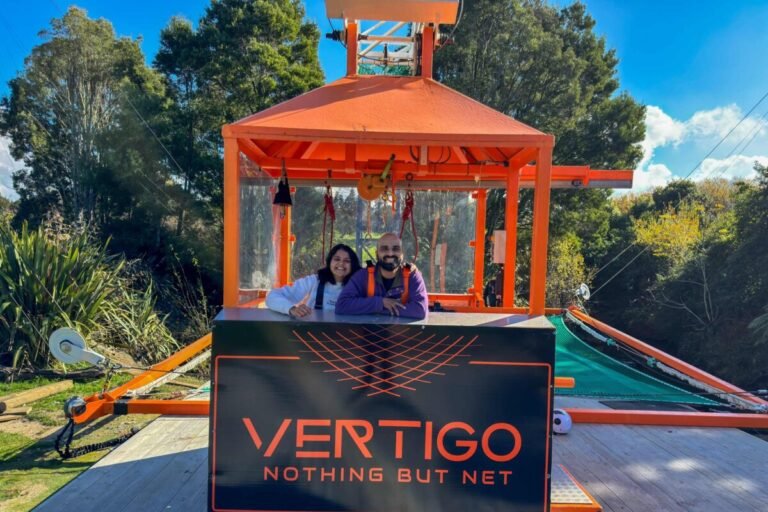 Sagar and Ami smiling in front of the Vertigo Nothing But Net sign at Velocity Valley Rotorua after the freefall