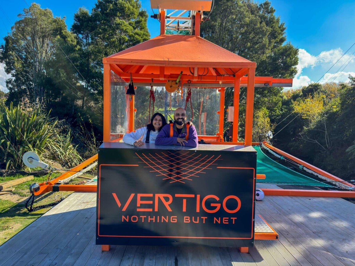 Sagar and Ami smiling in front of the Vertigo Nothing But Net sign at Velocity Valley Rotorua after the freefall